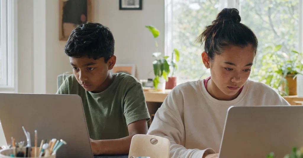 Two children at an AI summer camp for kids ages 8 to 16 working on laptops