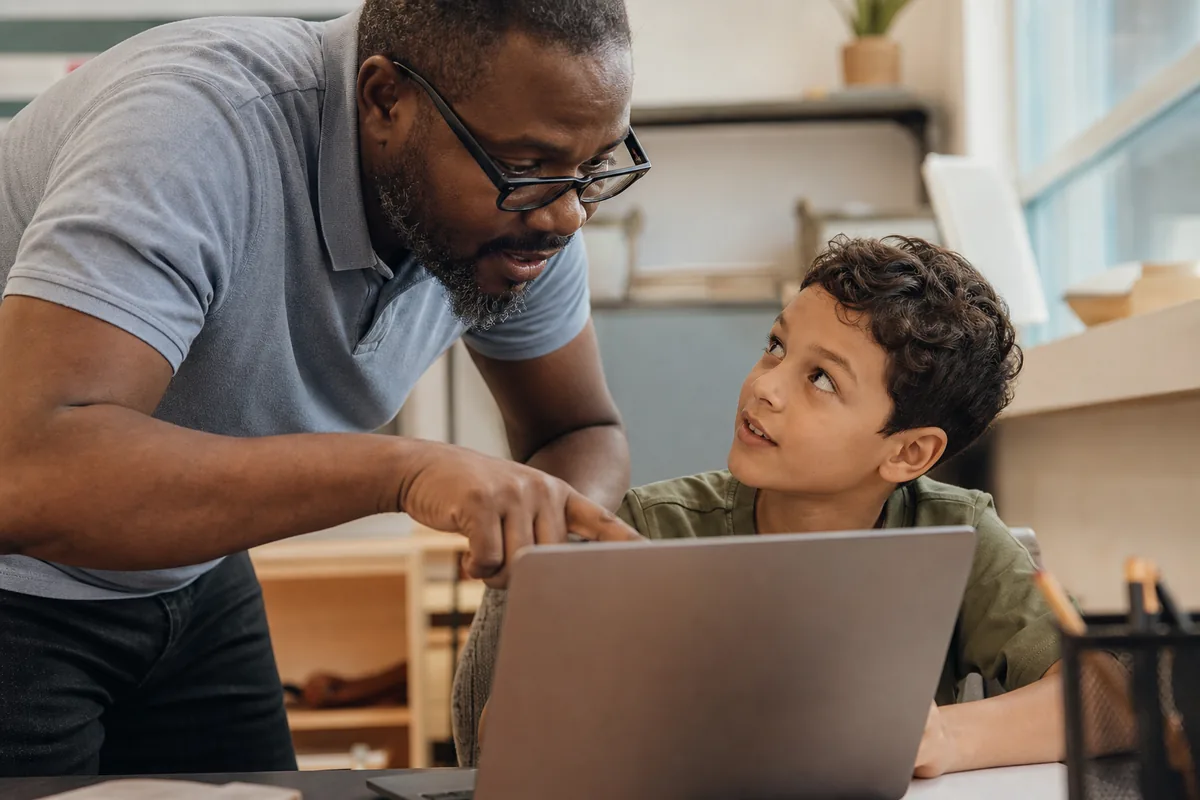 An instructor redirecting a child to review an AI prompt and output carefully