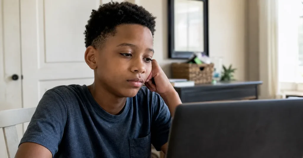 A child sitting alone at a laptop staring at a screen - will AI make kids lazy