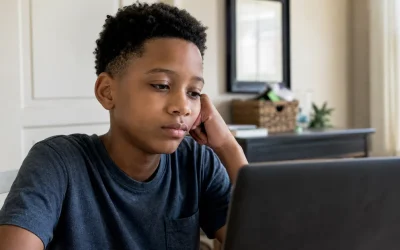 A child sitting alone at a laptop staring at a screen - will AI make kids lazy